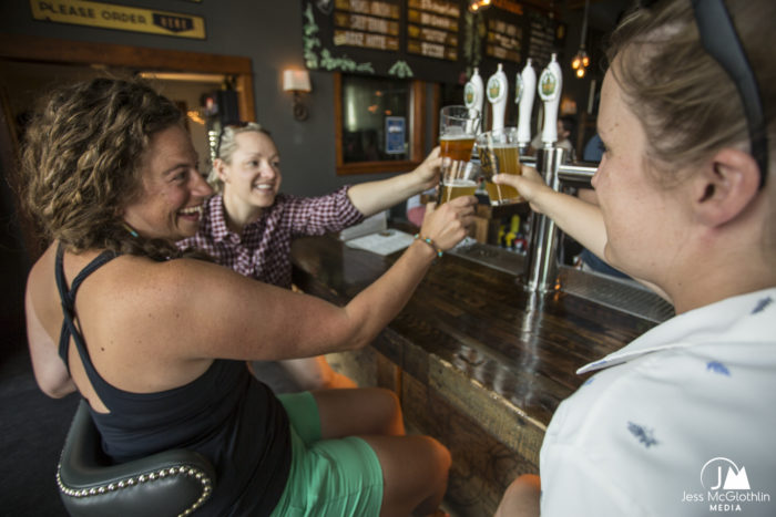 Three friends toast each other with beer at MAP Brewing in Bozeman, Montana.